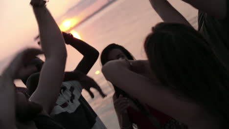 Group-Of-Friends-Having-Fun-And-Dancing-Raising-Their-Arms-In-A-Party-At-Sunset