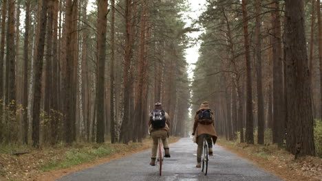 Rückansicht-Eines-Paares-In-Winterkleidung,-Das-Bei-Regen-Fahrrad-Im-Wald-Fährt-1