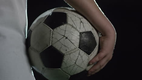Camera-Focuses-Soccer-Ball-Held-By-Boy-Illuminated-By-A-Spotlight-At-Night