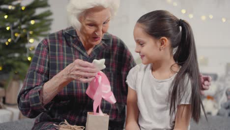 Glückliche-Großmutter,-Die-Weihnachtsgeschenk-Von-Der-Kleinen-Enkelin-öffnet-Und-Sie-Umarmt