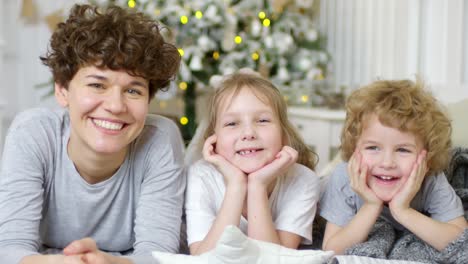 Portrait-Of-Beautiful-Mother,-Little-Daughter-And-Cute-Son-Lying-Together-On-Bed-And-Smiling-At-Camera-On-Christmas