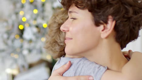 Porträt-Der-Liebevollen-Mutter,-Die-Ihren-Kleinen-Sohn-Zu-Weihnachten-Zu-Hause-Umarmt-Und-Küsst