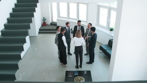 Several-Intercultural-Business-Partners-Standing-In-Circle-Inside-Office-And-Listening-To-Mature-Head-Of-Company-Giving-Them-Instructions