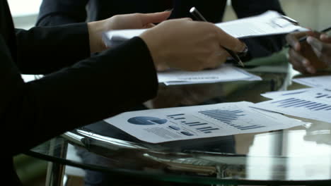 Close-Up-View-Of-Business-People-Holding-Documents-On-A-Table