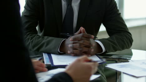 Close-Up-View-Of-Afroamerican-Businessman-Ina-Meeting-With-Coworkers-Sitting-At-A-Table,-While-Discussing-Details-Of-A-Project