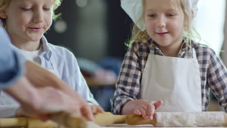 Children-Of-Elementary-School-Age-Kneading-Dough-Together-And-Enjoying-Cooking-In-Kitchen