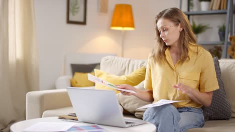 Female-Teacher-Sitting-On-Sofa-Having-Online-Class-At-Home-And-Showing-Charts-And-Statistics