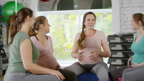 Tres-Mujeres-Embarazadas-En-Forma-Sentadas-En-Círculo-Sobre-Colchonetas-De-Yoga-Y-Hablando