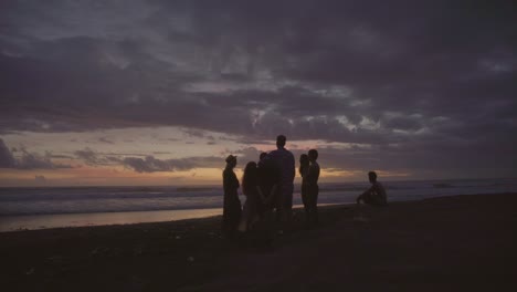 Gruppe-Von-Freunden,-Die-Am-Strand-An-Der-Küste-Von-Bali-Stehen-Und-Sich-Abends-Unterhalten