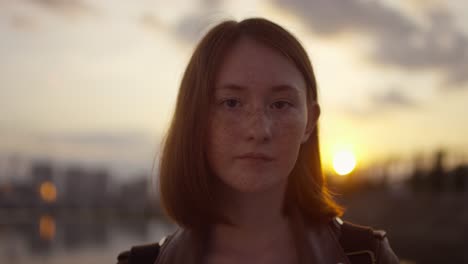 Porträt-Eines-Jungen-Mädchens-Mit-Roten-Haaren-Und-Sommersprossen,-Das-Bei-Sonnenuntergang-In-Die-Kamera-Blickt