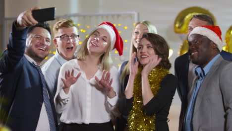 Oficinistas-Felices-Con-Sombreros-De-Oropel-Y-Santa-Haciendo-Muecas-Y-Tomando-Selfie-Juntos-En-La-Fiesta-De-Navidad-En-El-Trabajo