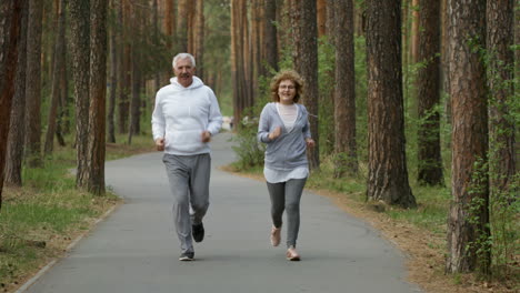 Happy-Elderly-Man-And-Woman-Smiling-And-Running-Along-Pavement-In-Park