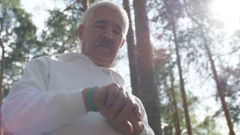 Low-Angle-View-Of-Senior-Man-With-Grey-Hair-And-Moustache-Walking-In-Forest-And-Touching-Screen-Of-Fitness-Wristwatch