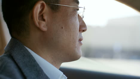 Close-Up-View-Of-Face-Of-Concentrated-Middle-Aged-Man-In-Glasses-Driving-Car-On-City-Road-In-The-Morning