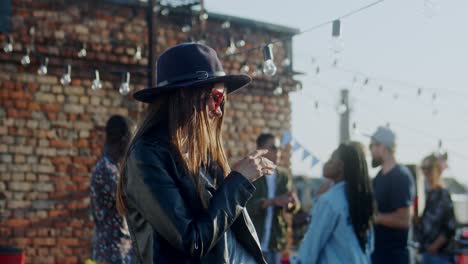 Young-Stylish-And-Beautiful-Girl-In-Black-Sunglasses-And-Hat-Dancing-Cheerfully-In-Front-Of-The-Camera-At-The-Rooftop-Party-At-Daytime-1