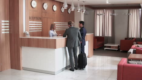 Two-Businessmen-Check-In-At-A-Hotel-Front-Desk