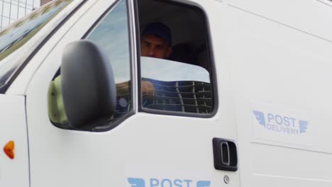 Tracking-Shot-Of-Man-In-Blue-Uniform-Driving-Mail-Delivery-Van-In-City