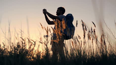 A-Young-Backpacker-Walks-Through-A-Wheat-Field-At-Dusk