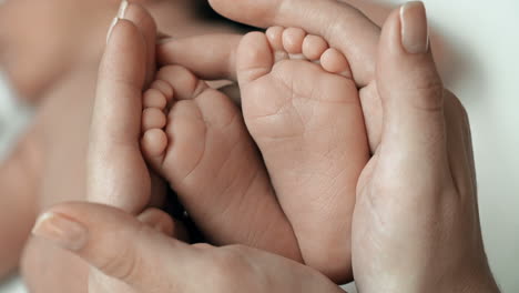 Close-Up-Of-Little-Baby-Feet-In-Hands-Of-Unrecognizable-Mother
