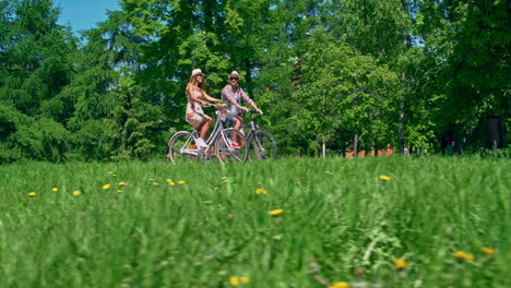 Kamerafahrt-Eines-Paares,-Das-Im-Park-Fahrrad-Fährt-Und-Sich-Im-Sommer-Unterwegs-Unterhält