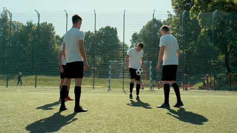 Gruppe-Junger-Fußballspieler,-Die-An-Einem-Sonnigen-Tag-Auf-Einem-Straßenfußballplatz-Trainieren-Und-Sich-Gegenseitig-Ball-Zuspielen