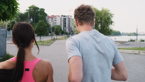 Back-View-Of-A-Young-Couple-Running-Together-In-An-Urban-Park-In-The-City-Near-A-River