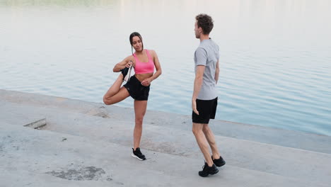 Sportive-Couple-Warming-Up-And-Stretching-Near-The-River