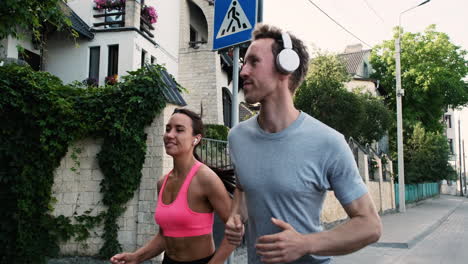 Beautiful-Runner-Girl-Wearing-Airpods-And-Sportive-Young-Man-With-Headphones-Running-Together-In-The-City-1