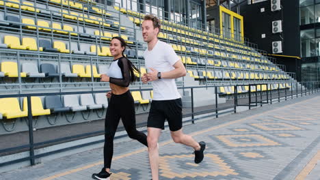 Happy-Sportive-Couple-Talking-And-Running-Together-In-The-Stadium