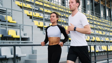 Happy-Sportive-Couple-Talking-And-Running-Together-In-The-Stadium-2