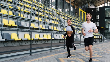 Smiling-Sportive-Couple-Running-Together-In-The-Stadium