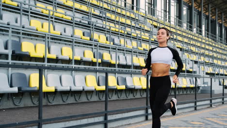 Pretty-Fit-Girl-Wearing-Airpods-Running-In-The-Stadium-In-The-Morning