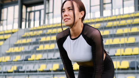 Tired-Beautiful-Woman-Resting-With-Hands-On-Knees-After-Running-Workout-In-The-Stadium