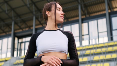 Beautiful-Smiling-Fit-Girl-Resting-And-Checking-Smartwatch-After-Running-Workout-In-The-Stadium