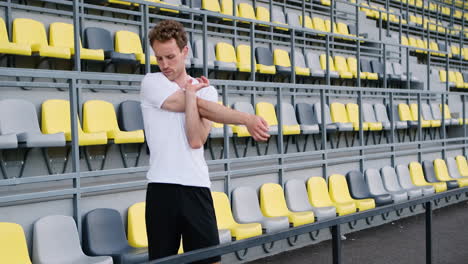 Fitness-Young-Male-Athlete-Stretching-Arms-In-The-Stadium