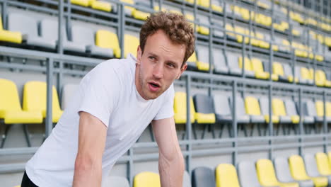 Tired-Fitness-Young-Male-Athlete-Resting-While-Leaning-On-Metal-Railings-In-The-Stadium