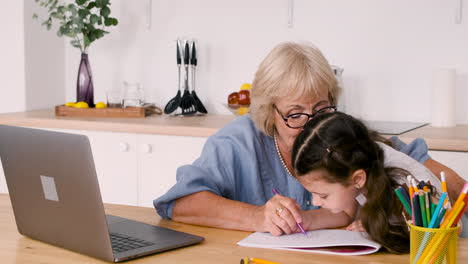 Grandmother-And-Granddaughter-Drawing-Together-Sitting-At-Table-In-Kitchen