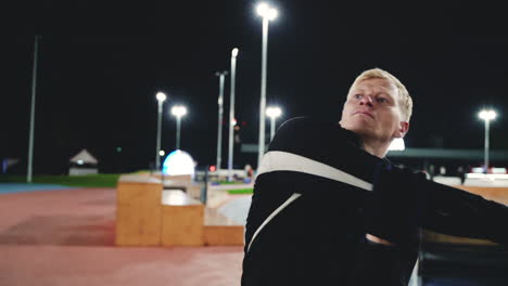 Sportive-Blond-Man-Doing-Stretching-Exercises-Before-Training-In-The-Park-At-Night-3
