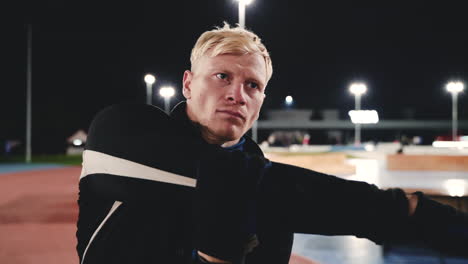 Sportive-Blond-Man-Doing-Stretching-Exercises-Before-Training-In-The-Park-At-Night-4