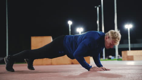 Sportive-Blond-Man-Doing-Push-Up-Exercises-In-The-Park-At-Night