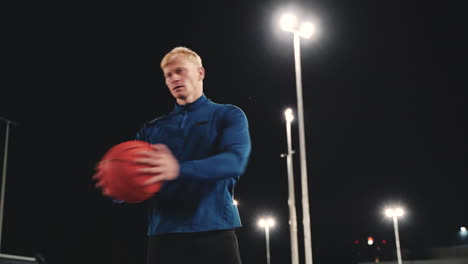 Sportive-Blond-Man-Doing-Rotation-Core-Exercises-Using-Basketball-In-The-Park-At-Night