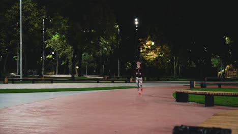 Sportive-Sportswoman-Using-Bluetooth-Headphones-Running-In-The-Park-At-Night