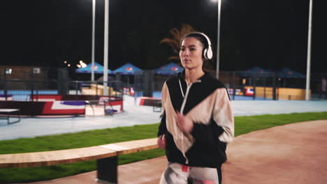 Sportive-Sportswoman-Using-Bluetooth-Headphones-Running-In-The-Park-At-Night-1