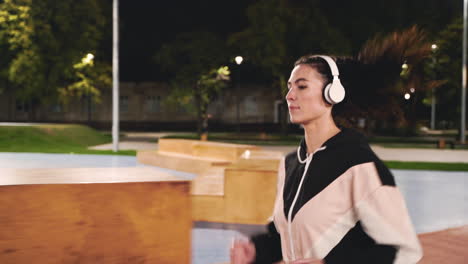 Sportive-Sportswoman-Using-Bluetooth-Headphones-Running-In-The-Park-At-Night-2