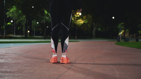 Back-View-Close-Up-Of-A-Fit-Girl-Stretching-Legs-And-Then-Running-In-The-Park-At-Night