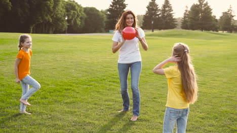 Happy-Mother-And-Her-Two-Little-Daughters-Playing-With-Ball-On-Meadow-1