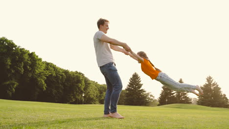Happy-Father-Holding-Her-Little-Daughter-And-Spinning-Around-On-Meadow-In-The-Park-1
