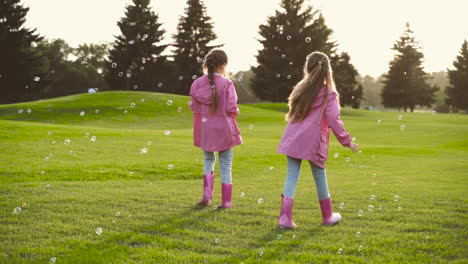 Glückliche-Kleine-Schwestern-In-Identischer-Kleidung,-Die-Im-Park-Seifenblasen-Fangen-1