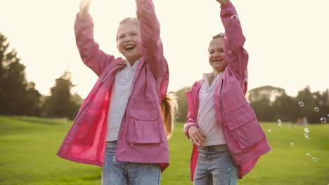 Happy-Little-Sisters-In-Identical-Clothes-Catching-Soap-Bubbles-In-The-Park-2