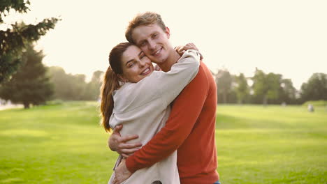 Happy-Couple-Smiling-At-Camera-And-Hugging-In-The-Park